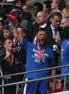 Millwall FC Celebrates Promotion to League One: Darren Ward Lifts the Play-Off Trophy at Wembley Stadium